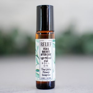 May include: A brown glass roll-on bottle with a black cap and a white label that reads "RELIEF ITCH & BUG BITE AFTER CARE essential oil ROLL ON The Little Flower Soap Co 0.3502/10.35ML".