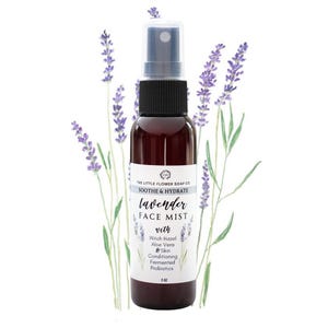 May include: A dark brown face mist bottle with a black cap and spray nozzle. The label reads "lavender FACE MIST" with additional text. Lavender sprigs and leaves are in the background. The bottle contains 2 fl oz of product.