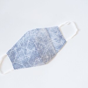 May include: A blue and white patterned face mask with white elastic straps.