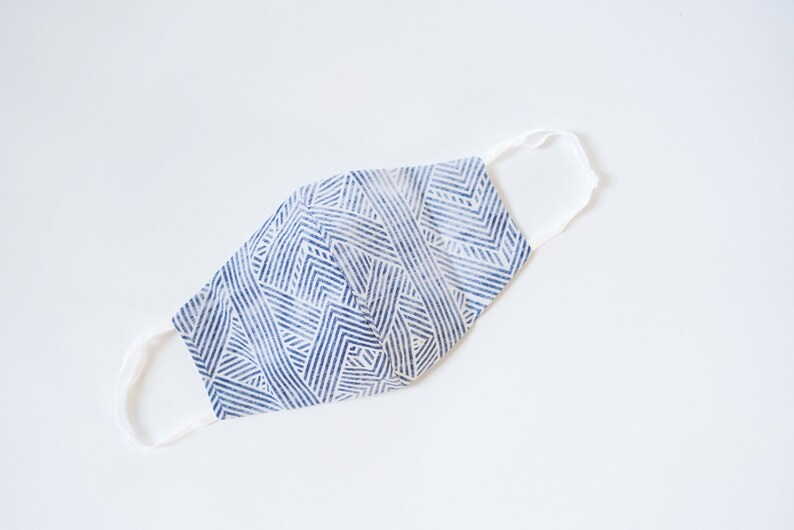 May include: A blue and white patterned face mask with white elastic straps.