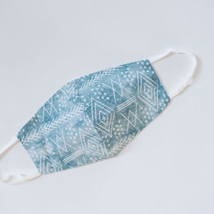 May include: A blue and white patterned face mask with white elastic straps.