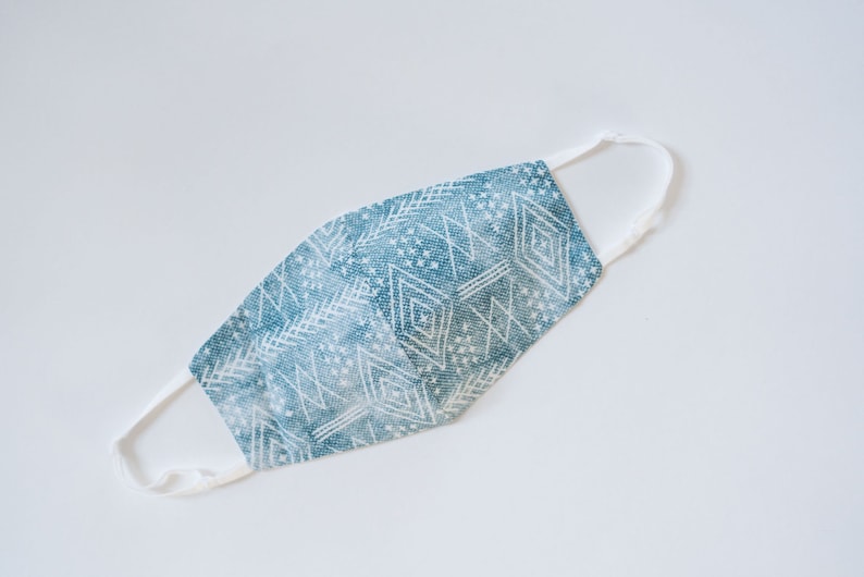 May include: A blue and white patterned face mask with white elastic straps.