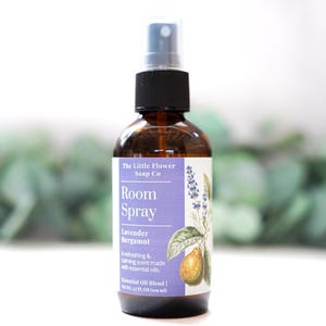 May include: A brown glass room spray bottle with a black cap and spray nozzle. The label features the text "Room Spray Lavender Bergamot" with botanical illustrations. The bottle contains 4 fl oz (118 ml) of essential oil blend.