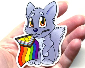 May include: A sticker featuring a cartoon wolf with gray fur, large yellow eyes, and a black stick in its mouth. The wolf is holding a rainbow flag with a progressive pride flag design. The sticker has a white border.