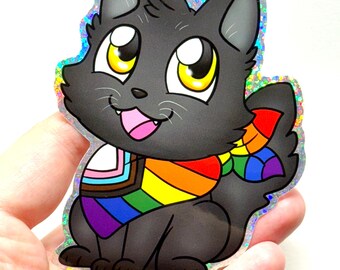 May include: A black cat sticker with large yellow eyes and a rainbow scarf. The sticker has a holographic border and a pink tongue. The scarf features the colors of the Pride flag and the transgender flag.