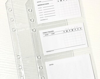 May include: Clear plastic binder inserts with three pockets, each holding a white card. The top card has spaces for "Month" and "Important Dates" with a calendar grid. The middle card is a "Weekly Tracker" with spaces for "Mood" and "Habit". The bottom card is for "Notes".