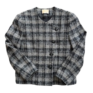 May include: A gray and black plaid jacket with a round collar and three black buttons. The jacket has long sleeves and a small label near the collar. The fabric has a woven texture.