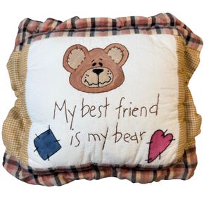 May include: A square throw pillow with a white center panel featuring an embroidered brown bear face, the text "My best friend is my bear," a blue square patch, and a pink heart patch. The pillow has a ruffled border in a tan and brown plaid pattern.
