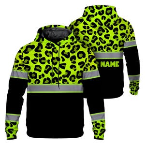 Könnte beinhalten: Ein neongrüner und schwarzer Kapuzenpullover mit Leopardenmuster. Der Hoodie hat einen reflektierenden silbernen Streifen über der Brust und den Ärmeln, mit dem Wort "NAME" auf der Rückseite.