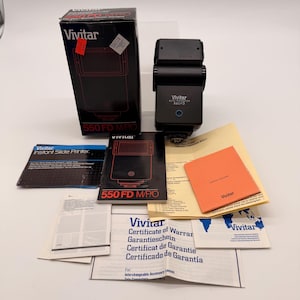 以下が含まれることがあります： 黒色のVivitar 550 FD MPOフラッシュユニット。オリジナルの箱と書類が付属しています。箱とフラッシュユニットには赤いアクセントがあります。マニュアル、保証情報、オレンジ色のオーナーズレコードが含まれています。
