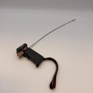 May include: Black and brown remote control with a long, thin antenna. The remote has a brown trigger and a leather wrist strap. The word "ESCO" is visible on the remote.
