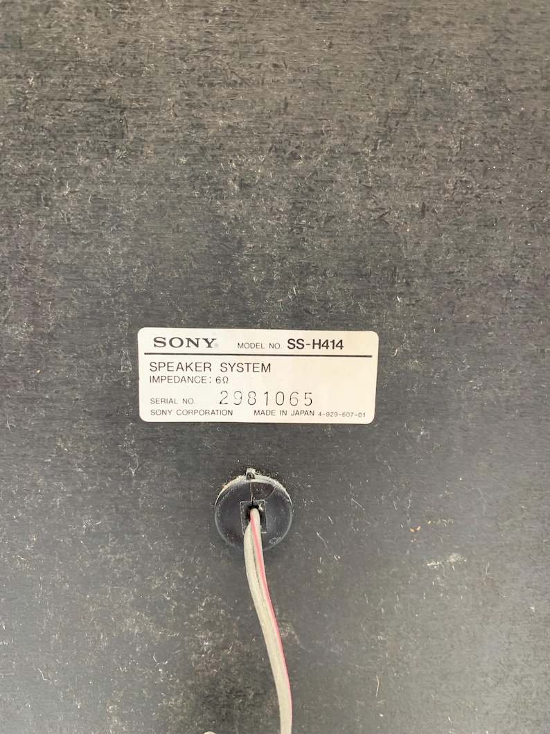 May include: A black Sony speaker system, model number SS-H414, with an impedance of 6 ohms. The label includes the serial number 2981065 and states it was made in Japan. A two-wire speaker cable extends from a circular port below the label.