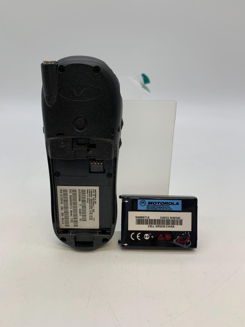 May include: A black Motorola cell phone with a detached battery. The phone has a Motorola logo and various labels with text. The battery is black with the Motorola logo and text including "SNN5671A" and "CELL ORIGIN CHINA".