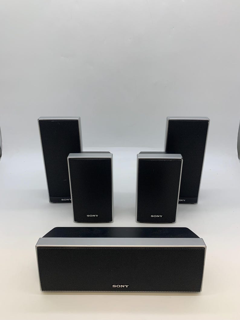 May include: A set of five black and silver Sony speakers. The collection includes one horizontal center speaker and four vertical satellite speakers, each featuring a black mesh front grille with the Sony logo printed in white at the bottom.