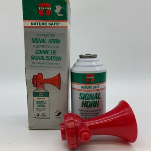 Könnte beinhalten: Ein rotes Tempo Nature Safe Signalhorn und seine Schachtel. Die Schachtel und das Horn sind weiß und grün mit den Worten "Signal Horn" in großen Buchstaben. Die Schachtel hat auch französischen Text.