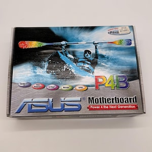 Może przedstawiać: Prostokątne pudełko ASUS P4B Motherboard. Pudełko zawiera grafikę kajakarza z kolorową wiosłem na niebieskim tle. Tekst "P4B Motherboard" jest wyraźnie wyświetlony, wraz z logo ASUS.