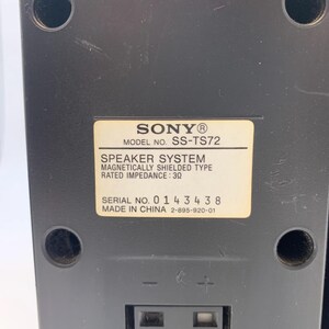 May include: A black Sony speaker system, model SS-TS72, featuring a rectangular label with technical specifications including a rated impedance of 3 ohms, a serial number 0143438, and a made in China marking, with two spring-clip wire terminals.