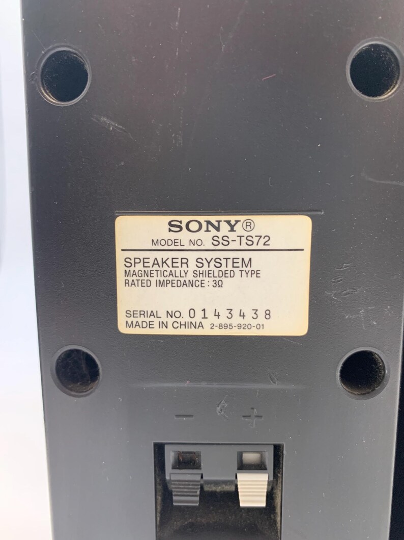 May include: A black Sony speaker system, model SS-TS72, featuring a rectangular label with technical specifications including a rated impedance of 3 ohms, a serial number 0143438, and a made in China marking, with two spring-clip wire terminals.
