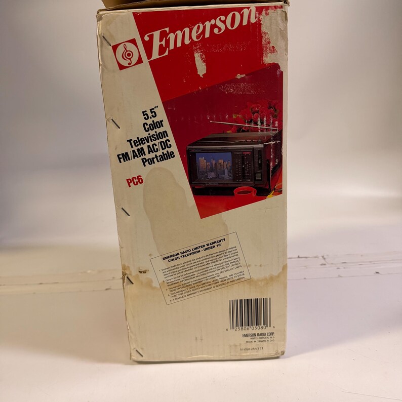 K&ouml;nnte beinhalten: Vintage Emerson-Box mit dem Markennamen in Rot. Die Box enth&auml;lt den Text "5,5" Color Television FM/AM AC/DC Portable PC6." Ein Bild eines kleinen Fernsehers ist ebenfalls sichtbar.