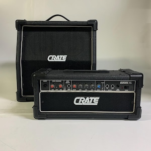 May include: Two black Crate amplifiers, a speaker cabinet and a combo amplifier. The speaker cabinet has a handle and the Crate logo in white. The combo amplifier has control knobs, the G200C XL model name, and the Crate logo.