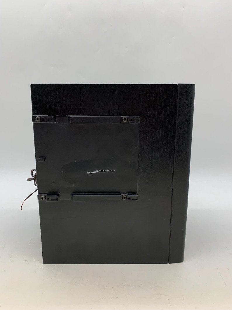 May include: A rectangular black wooden frame with a smooth finish, featuring a central black plastic mounting bracket attached to the back. The frame has a solid construction with visible wood grain texture and a thin wire extending from the side.