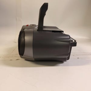 K&ouml;nnte beinhalten: Ein dunkelgraues tragbares Radio mit CD-Player, ausgestattet mit einem seitlichen Lautsprecher mit schwarzem Netzgitter, einem aufrechten Tragegriff an der Oberseite und einer d&uuml;nnen Metallantenne, die aus der R&uuml;ckseite des Geh&auml;uses ragt.