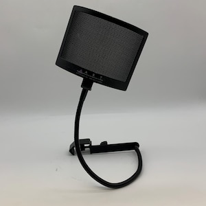 以下が含まれることがあります： メッシュスクリーンを備えた黒いポップフィルター。フレキシブルなグースネックアームとベースに取り付けられています。このフィルターは、ボーカル録音における破裂音と歯擦音を低減するように設計されています。「ART」というブランド名が見えます。