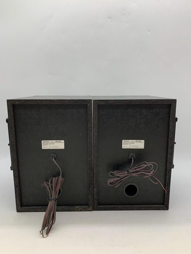 May include: Two black Sony SS-H65 speaker systems shown from the rear. Each unit features a rectangular wooden cabinet, a central circular port, and a white identification label with the text SONY SS-H65 SPEAKER SYSTEM, along with serial numbers.