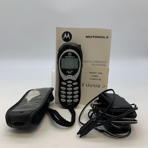 May include: A black Motorola 120c digital wireless telephone with a keypad, screen, and antenna. Included are a black carrying case, charger, and user guide. The phone has the Motorola logo and model information printed on it.