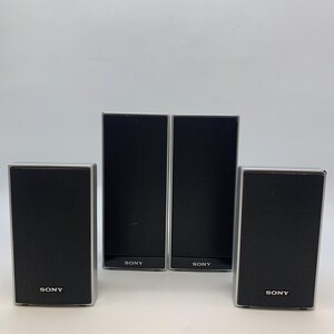 May include: Four rectangular Sony speakers with black mesh grilles and silver frames. Two speakers are taller and positioned in the center, while two shorter speakers are placed on the outer sides. Each speaker features the Sony logo in white text.