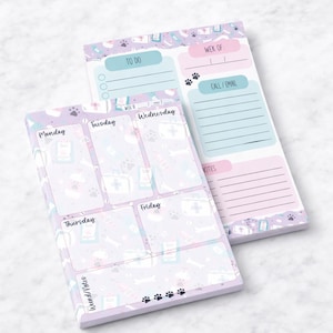 May include: Two rectangular notepads with a pastel purple and pink design. One notepad is a weekly planner with sections for each day, the other has a to-do list and space for notes. The design includes paw prints and medical symbols.