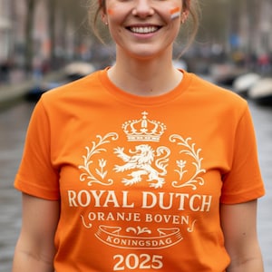 以下が含まれることがあります： 王冠、ライオン、そして「ROYAL DUTCH ORANJE BOVEN KONINGSDAG 2025」の文字が描かれた白いグラフィックデザインの鮮やかなオレンジ色のTシャツ。Tシャツは半袖で、クルーネックです。