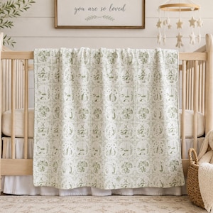 May include: A light green and white baby blanket featuring a repeating grid pattern of circular illustrations. The designs include scenes of bicycles, sailboats, and figures in a landscape, all rendered in a soft, monochromatic green line art style.