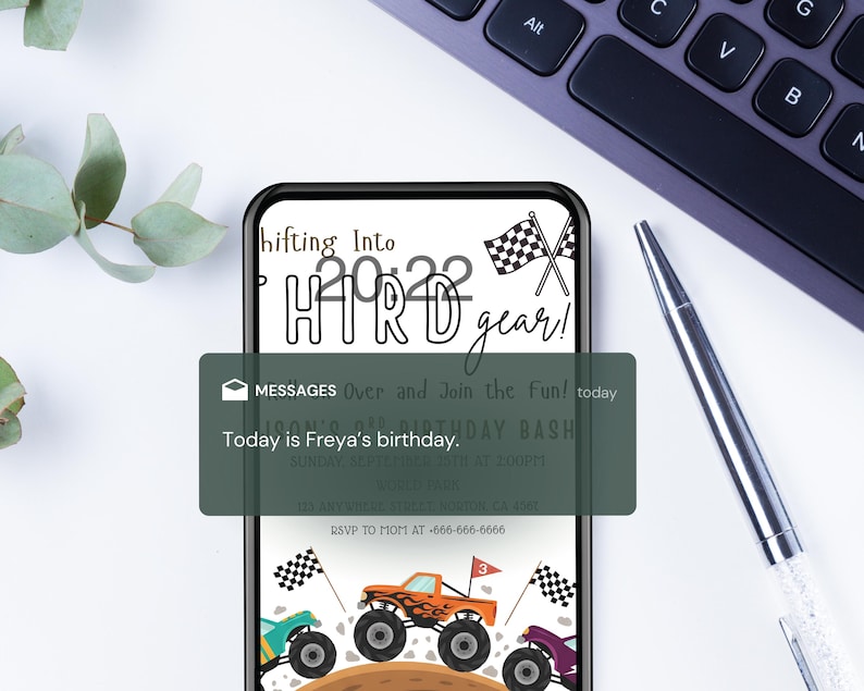 May include: A smartphone displays a birthday invitation with monster trucks and checkered flags. The text reads "Shifting Into HTRD gear!" and "Today is Freya's birthday." A pen and keyboard are in the background.