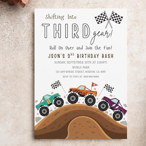 May include: A birthday party invitation with the text "Shifting Into THIRD gear!" and "JSON'S 3RD BIRTHDAY BASH". The invitation features illustrations of three colorful monster trucks racing over a brown hill, with checkered flags.