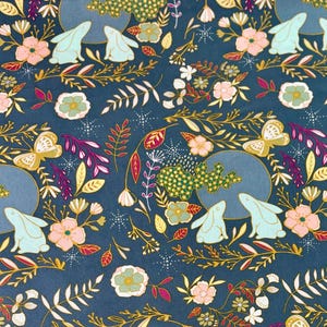 May include: Dark teal fabric with a repeating pattern of rabbits, flowers, butterflies, and foliage. The design includes light blue rabbits, pink and gold flowers, and gold butterflies. The fabric is 100% premium cotton.