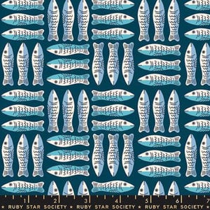 May include: A dark blue fabric featuring a repeating pattern of light blue and white fish oriented both horizontally and vertically. The bottom edge displays a black border with the white text Ruby Star Society and a ruler with 7 inches.