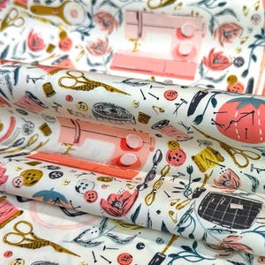 May include: White fabric with a repeating pattern of sewing tools, including scissors, sewing machines, spools of thread, and buttons. The design features a color palette of pink, gold, black, and green.