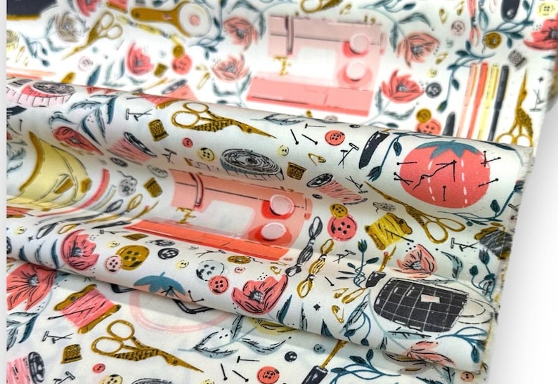 May include: White fabric with a repeating pattern of sewing tools, including scissors, sewing machines, spools of thread, and buttons. The design features a color palette of pink, gold, black, and green.