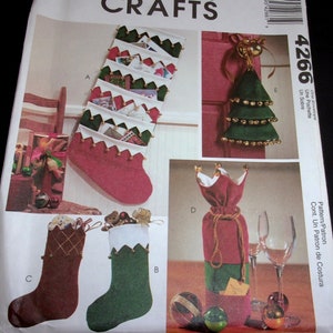 May include: A McCall's Crafts pattern featuring Christmas stocking designs. The image shows various stocking styles, including a red stocking with pockets, a green Christmas tree ornament, and wine bottle gift bags. The pattern includes the number 4266.