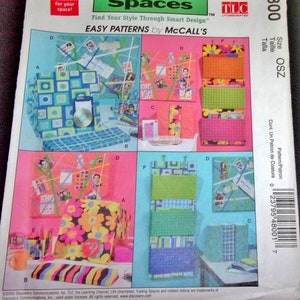 May include: A sewing pattern for a set of three storage boxes. The boxes are decorated with different patterns, including geometric shapes, flowers, and stripes. The pattern is titled "Trading Spaces" and is from McCall's. The pattern number is M4800.