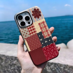 May include: A patterned phone case with a patchwork design. The case features a mix of red, cream, and navy blue squares with heart, plaid, and floral patterns. The phone case has a dark grey border and a multi-lens camera cutout.