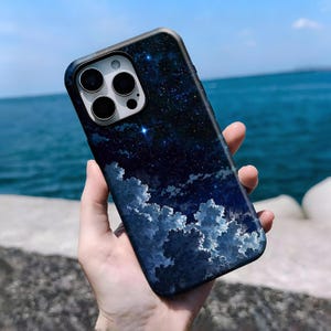 May include: A smartphone case featuring a night sky design with stars and clouds. The case has a dark blue background with white and light blue clouds at the bottom. The phone case has a camera cutout.