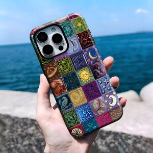 May include: A smartphone case featuring a grid of colourful square tiles. Each tile displays distinct imagery including a sun, moon, stars, a spider web, floral patterns, a bird, and human faces in shades of blue, green, purple, yellow, and red.