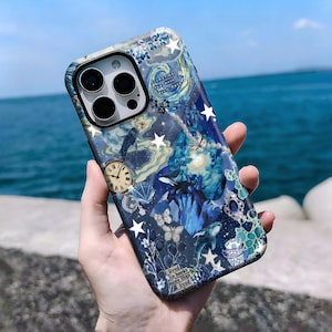 May include: A blue and white phone case with a whimsical design featuring stars, butterflies, a clock, and whales. The case has a quote that reads "I lived in books more than I lived anywhere."