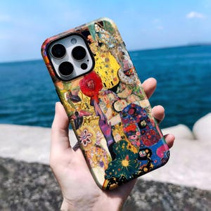 Peut inclure: Une coque de smartphone arborant un imprimé artistique aux couleurs vives inspiré de l'œuvre de Gustav Klimt. Le motif présente des détails complexes, des accents dorés et des figures stylisées dans des tons jaune, bleu, rouge et vert.