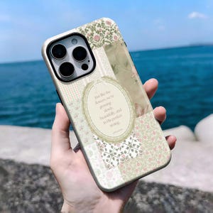 May include: A floral patterned phone case with a cream-colored border. The case features a patchwork design with various floral and botanical patterns in shades of green, pink, and cream. Text on the case reads: "Just like the flowers, we're growing slowly, beautifully, and in His perfect timing."