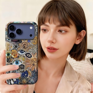 May include: A detailed phone case with an intricate design, featuring celestial and eye symbols in gold, blue, and silver. The case has a textured, artistic look. The phone case is designed for a modern smartphone, offering both style and protection.