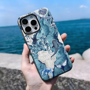 May include: A phone case featuring a blue and white map design with illustrations of marine life, including sharks, a turtle, and whale tails. The case has a glossy finish and a camera cutout.