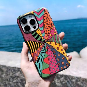 May include: A smartphone case featuring a vibrant, multi-coloured radial pattern. The design includes segments with various motifs such as hearts, peace signs, flowers, zigzags, and stripes in shades of orange, pink, teal, yellow, and dark blue.